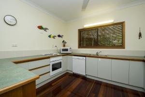 a kitchen with white cabinets and a clock on the wall at Marramaninjie in Arcadia