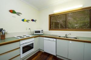 a kitchen with white cabinets and a sink and a microwave at Marramaninjie in Arcadia