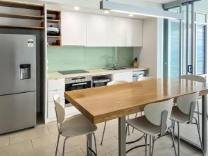 a kitchen with a wooden table and white cabinets at 1 Bright Point Apartment 4502 in Nelly Bay