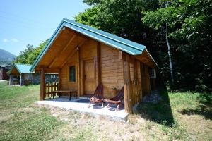 a small wooden cabin with two chairs and a table at Cottages Serdar in Mojkovac +9 photos