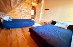 a bedroom with two beds and a wooden wall at Krustceles in Baltinava