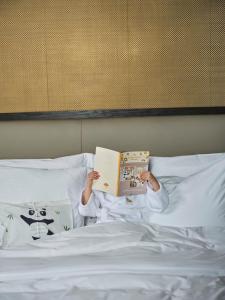 a child laying in bed reading a book at Mandarin Oriental Qianmen, Beijing in Beijing