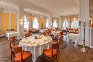 a restaurant with white tables and chairs and windows at Hotel Restaurant Bellevue au Lac in Thun