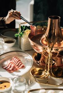 a person eating food on a table with plates of food at Mandarin Oriental Qianmen, Beijing in Beijing
