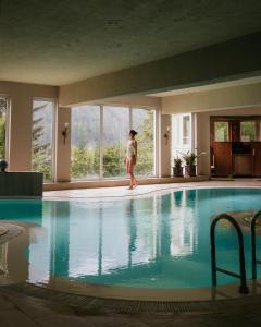 a woman standing in front of a swimming pool at Alpinresort Stubaierhof ****s in Fulpmes