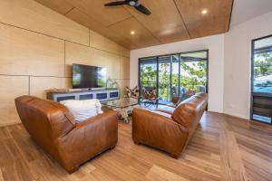 a living room with two leather chairs and a television at Headland House in Picnic Bay