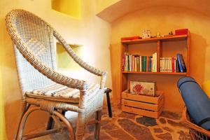 a wicker chair in a room with a book shelf at Chambre d'Hôtes La Chadeleufade in Chadeleuf