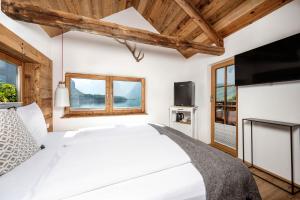 a bedroom with a white bed and a flat screen tv at Seehaus 96 Hallstatt in Hallstatt