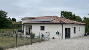 a small white house with solar panels on the roof at Chez Cathie & Didier in Revel