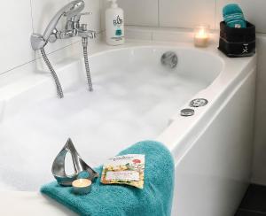 a bath tub with a blue towel and a sink at Sonnendeck 36 - Großenbrode in Grossenbrode
