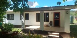 a small white house with a red door at Vatudei Homestay - Yasawa Islands in Somosomo