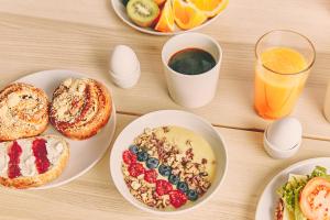 a table with plates of breakfast foods and a glass of orange juice at Break Sokos Hotel Flamingo in Vantaa