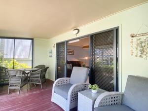 a patio with wicker chairs and a table on a balcony at Canopy Chalet 4 in Nelly Bay