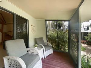 a porch with wicker chairs and sliding glass doors at Canopy Chalet 4 in Nelly Bay