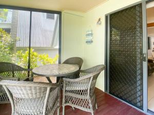 a patio with a table and chairs on a balcony at Canopy Chalet 4 in Nelly Bay
