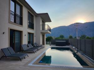 ein Haus mit Swimmingpool mit Liegestühlen und einem Gebäude in der Unterkunft Pronaos in Ortaca