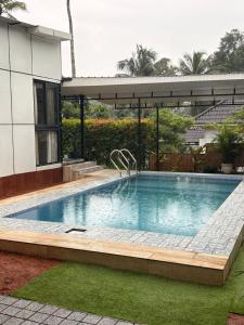 a large swimming pool in a yard with a house at Ginger Villa Farmstay, Thodupuzha in Idukki