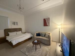 a bedroom with a bed and a chair and a tv at شادن للوحدات السكنية in Qufār