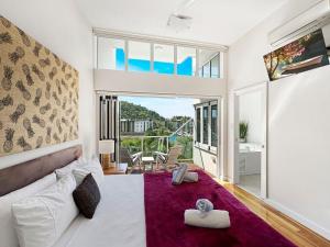 a bedroom with a white bed and a large window at Beachside Apartment 14 in Nelly Bay