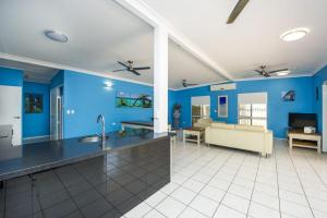 a kitchen with blue walls and a living room with a couch at Azure on Geoffrey Bay in Arcadia