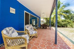 a porch with wicker chairs and a blue wall at Azure on Geoffrey Bay in Arcadia