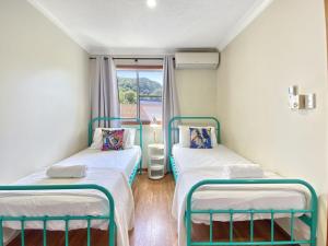 two twin beds in a room with a window at Island Magic Townhouse 5 in Arcadia