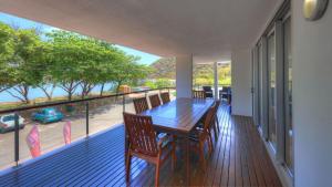 a wooden table and chairs on a deck with a balcony at Maggies Beachfront Apartment 10 in Horseshoe Bay