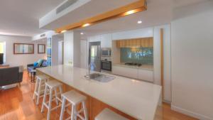 a kitchen with a large white counter with stools at Maggies Beachfront Apartment 10 in Horseshoe Bay +18 photos