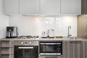a kitchen with a stove top oven next to a sink at Stylish 2-Bed Apartment by 888 Collins in Melbourne