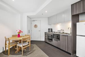 a kitchen with a table and chairs and a refrigerator at Stylish 2-Bed Apartment by 888 Collins in Melbourne