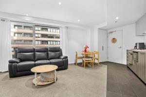 a living room with a black couch and a table at Stylish 2-Bed Apartment by 888 Collins in Melbourne