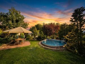 a pool in a yard with chairs and an umbrella at Chalupa u Macochy in Blansko