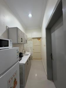 a white kitchen with a sink and a microwave at شادن للوحدات السكنية in Qufār