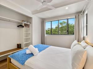 a white bedroom with a bed and a window at Picnic Point in Picnic Bay