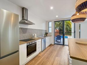 a kitchen with white cabinets and a counter with a table at Picnic Point in Picnic Bay