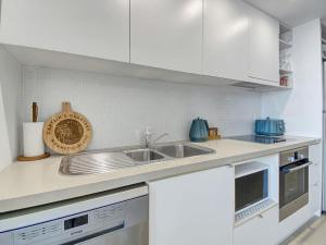 a white kitchen with a sink and a microwave at 1 Bright Point Apartment 1407 in Nelly Bay