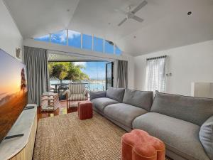 a living room with a gray couch and a tv at Waters Edge Townhouse 4 in Nelly Bay