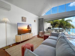 a living room with a couch and a flat screen tv at Waters Edge Townhouse 4 in Nelly Bay