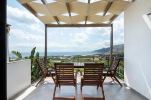 a balcony with a table and chairs and a view of the ocean at Casa di Olive Luxury Secluded Sea View Villa in South Crete in Goúdhouros