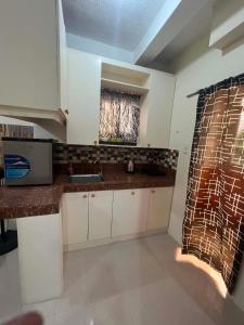 a kitchen with white cabinets and a sink and a window at DC Travellers Inn Unit E 3rd Fl in Malolos