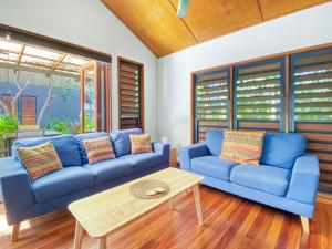 a living room with blue couches and a coffee table at Pure Magnetic Villa 4 in Nelly Bay