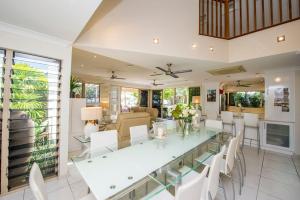 a dining room with a glass table and white chairs at Eeast on Picnic in Picnic Bay