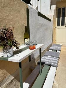 a white table with a bottle of wine and a plant at 166, Rodolfu in Sliema