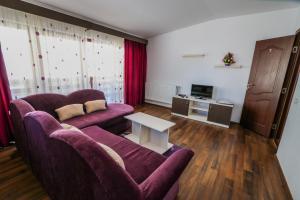 a living room with two purple couches and a table at Pensiunea Daria in Fundata