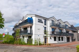 a white building with balconies on a street at Hotel Hafen Büsum in Büsum