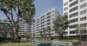 an apartment building with a swimming pool and trees at Modern Studio Pool View, King bed, BTS Punnawithi in Bangkok