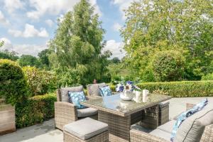 a patio with a table and chairs and trees at Finest Retreats - The Old Schoolhouse at Penrhos in Raglan