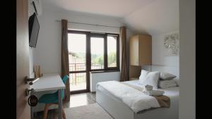 a bedroom with a bed and a desk and a window at Pensiunea Smiley in Turda