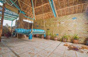 a porch with a blue bench in a room with plants at Kizingo Beach Eco Lodge in Lamu
