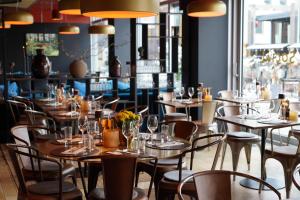 a restaurant with tables and chairs and windows at Clarion Hotel Gillet in Uppsala